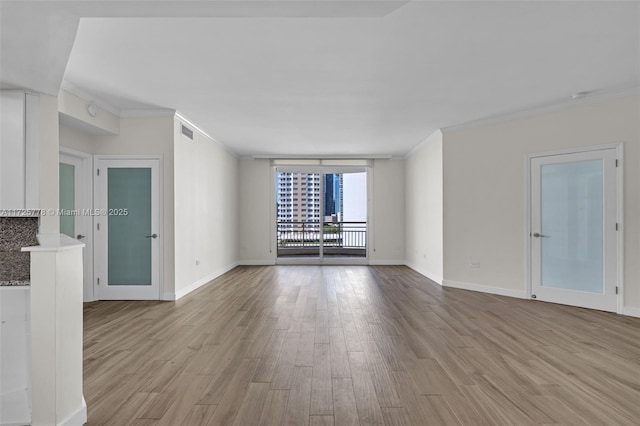 spare room with floor to ceiling windows, wood finished floors, baseboards, and ornamental molding