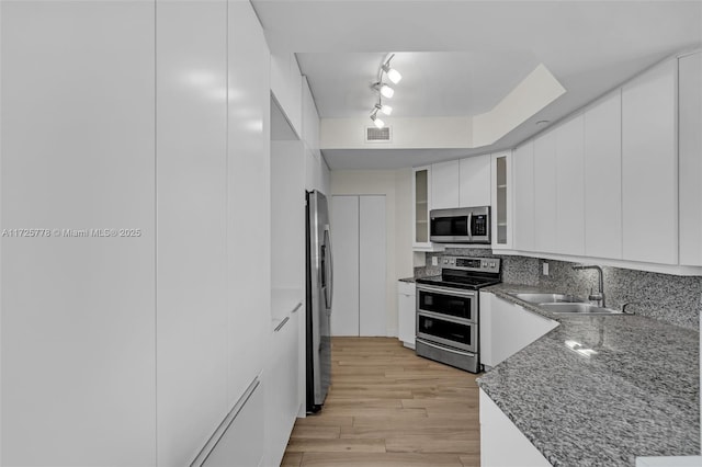 kitchen with visible vents, light wood-style flooring, a sink, stainless steel appliances, and white cabinets