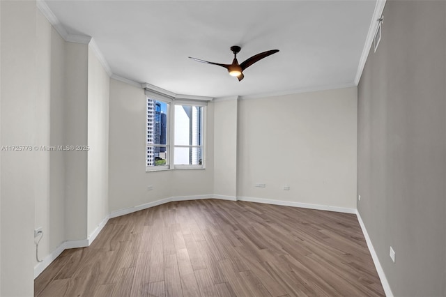 empty room with baseboards, wood finished floors, ornamental molding, and a ceiling fan