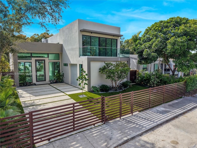 contemporary home with a balcony and a front lawn