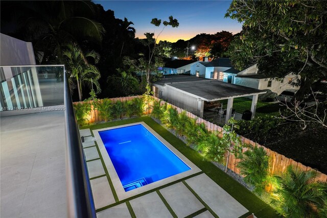 pool at dusk with a patio area