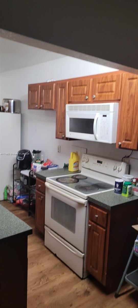 kitchen with white appliances and light hardwood / wood-style floors