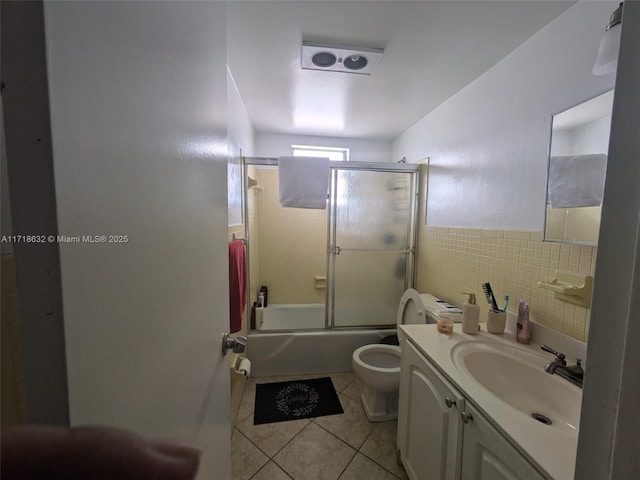 full bathroom featuring tile patterned flooring, toilet, vanity, tile walls, and shower / bath combination with glass door