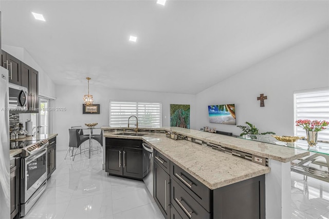 kitchen with sink, stainless steel appliances, vaulted ceiling, and pendant lighting