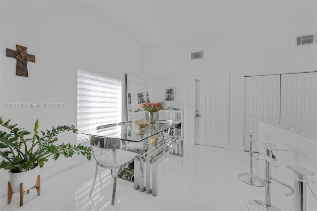 dining area with a towering ceiling and light tile patterned floors