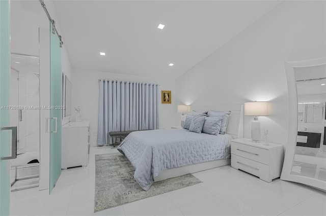 bedroom featuring lofted ceiling, ensuite bathroom, a barn door, and light tile patterned floors