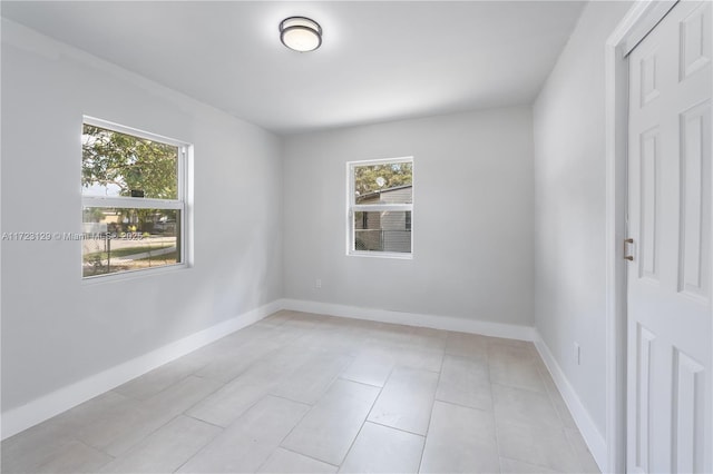 empty room with light tile patterned floors and a healthy amount of sunlight