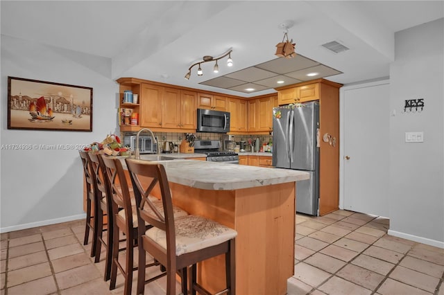 kitchen featuring tile countertops, a kitchen bar, backsplash, appliances with stainless steel finishes, and sink