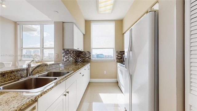 kitchen with sink, backsplash, white cabinetry, light tile patterned floors, and white appliances