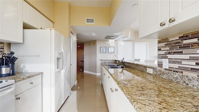 kitchen featuring white appliances, light stone countertops, light tile patterned floors, sink, and white cabinets