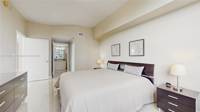 bedroom featuring light tile patterned floors and ensuite bath