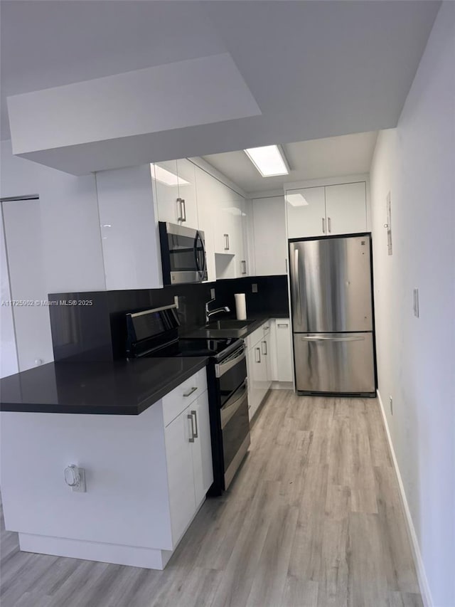 kitchen with white cabinetry, stainless steel appliances, light hardwood / wood-style flooring, and sink