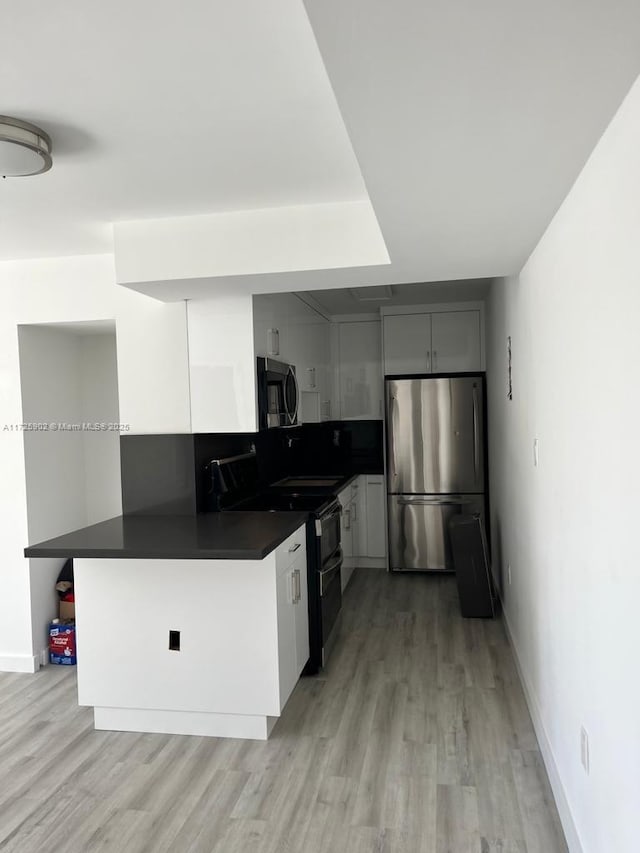 kitchen with appliances with stainless steel finishes, light hardwood / wood-style floors, gray cabinets, and kitchen peninsula