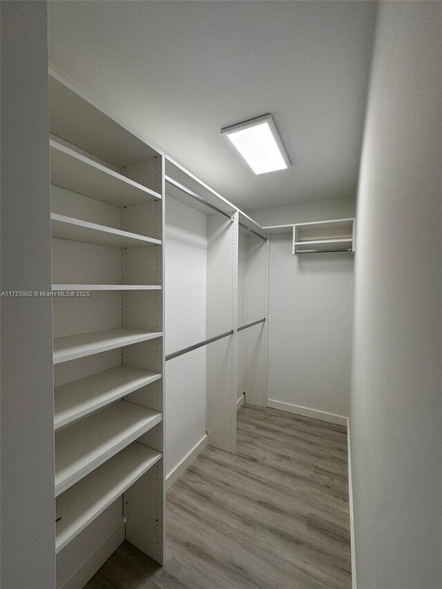 walk in closet with light hardwood / wood-style floors