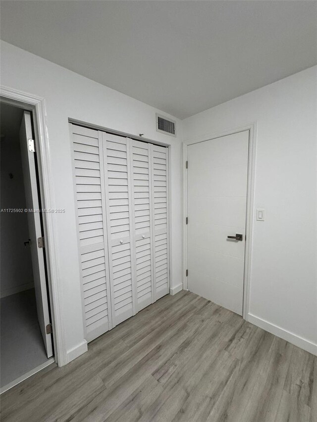 unfurnished bedroom featuring light hardwood / wood-style flooring and a closet