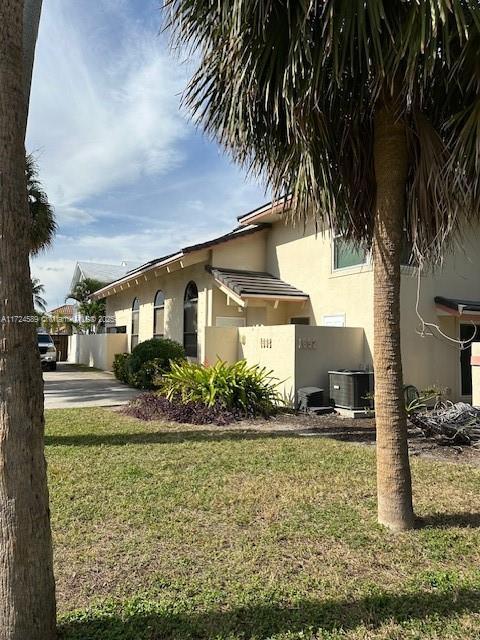 view of side of property with central AC unit and a yard