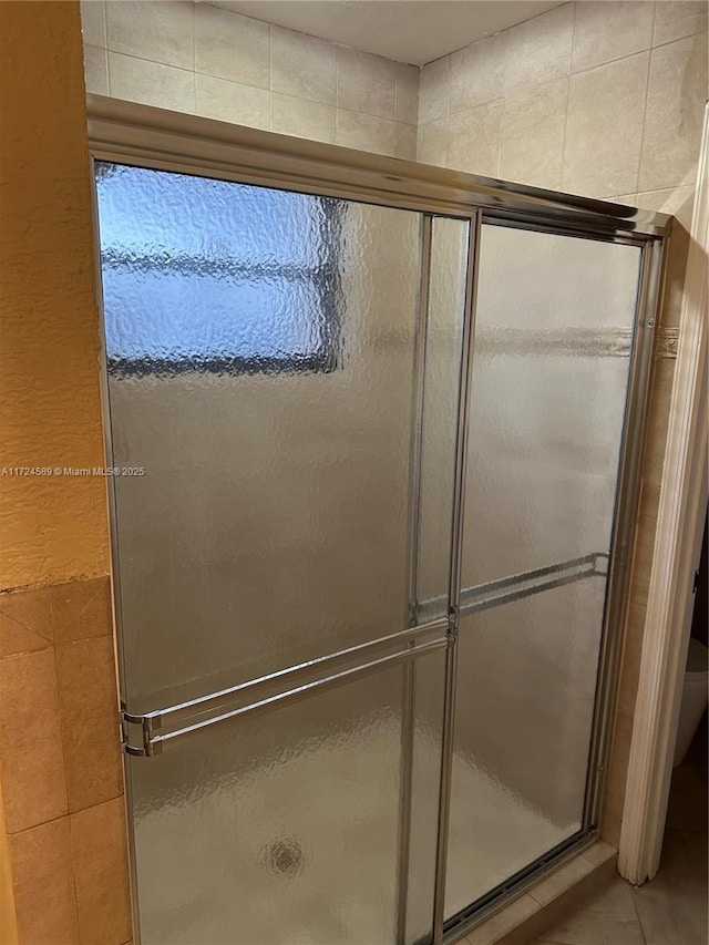 bathroom with a shower with shower door and tile patterned floors