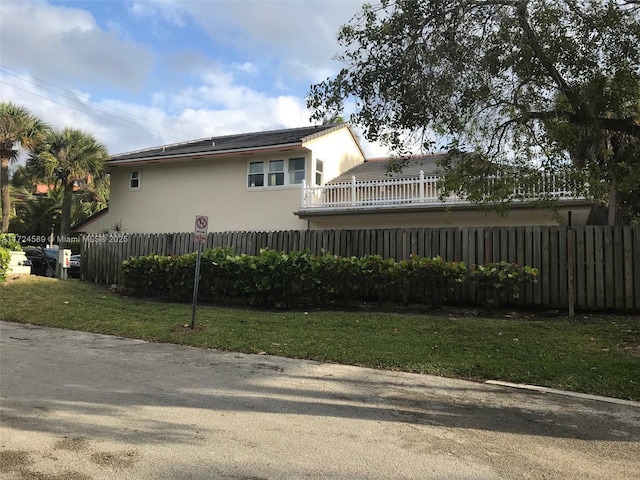 view of property exterior with a lawn and a balcony