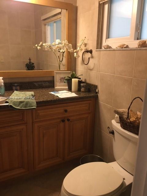 bathroom with toilet, vanity, and tile walls