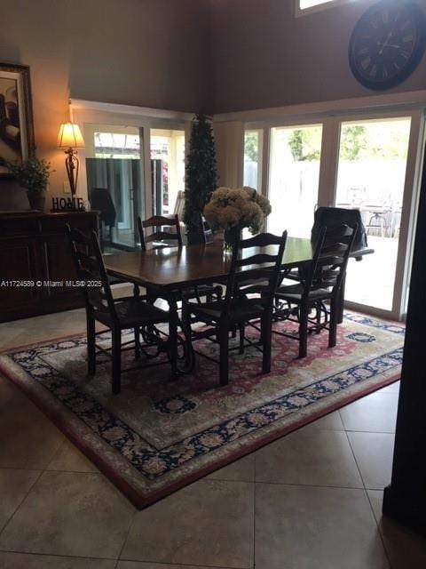 tiled dining area with plenty of natural light and a high ceiling