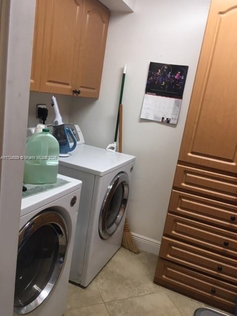 laundry room with cabinets, light tile patterned floors, and washer and clothes dryer