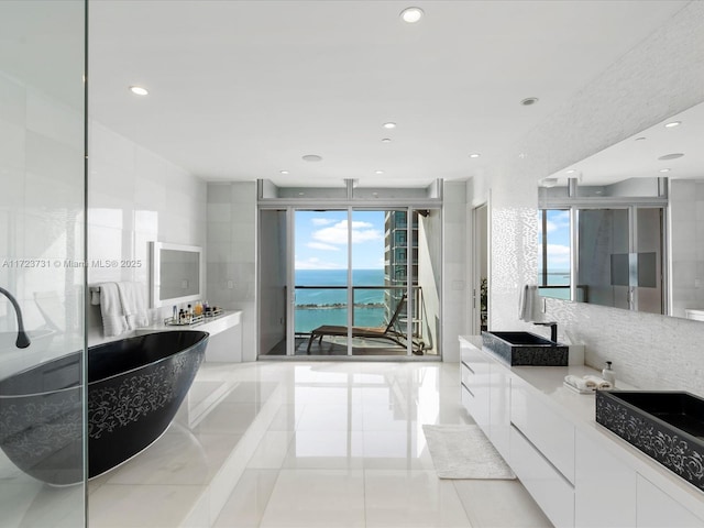 bathroom with a healthy amount of sunlight, separate shower and tub, a water view, and vanity