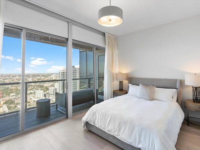 bedroom featuring floor to ceiling windows, access to outside, hardwood / wood-style floors, and multiple windows