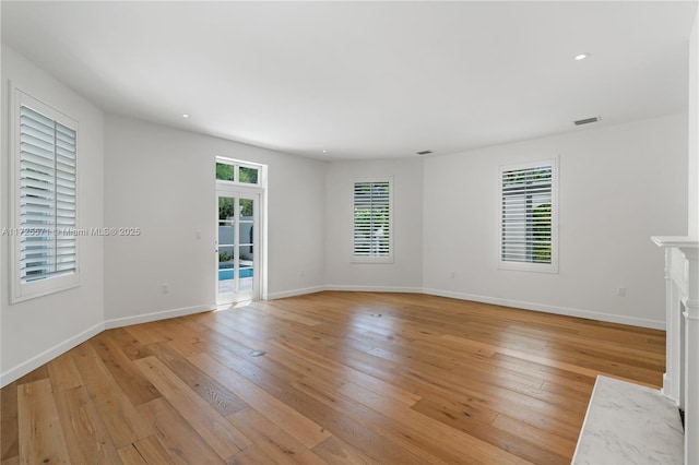 spare room featuring plenty of natural light, light hardwood / wood-style floors, and a premium fireplace