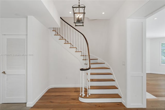 stairs with a chandelier and hardwood / wood-style floors