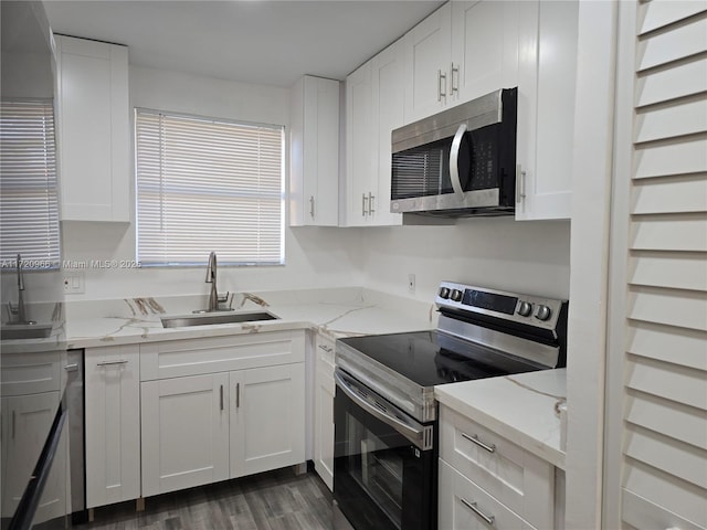 kitchen with light stone counters, dark hardwood / wood-style floors, white cabinetry, appliances with stainless steel finishes, and sink