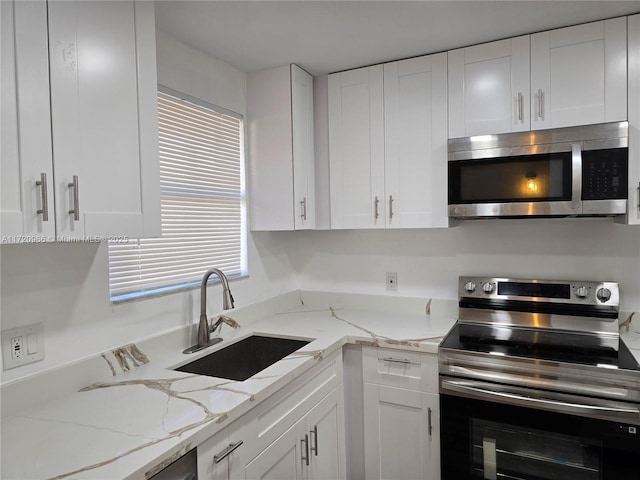 kitchen featuring sink, white cabinetry, light stone countertops, and appliances with stainless steel finishes