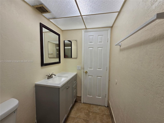 bathroom featuring toilet, tile patterned flooring, vanity, and a paneled ceiling