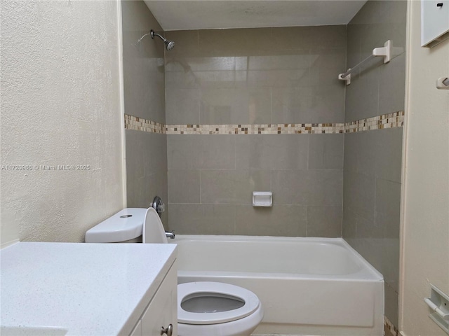 full bathroom with toilet, tiled shower / bath, and vanity