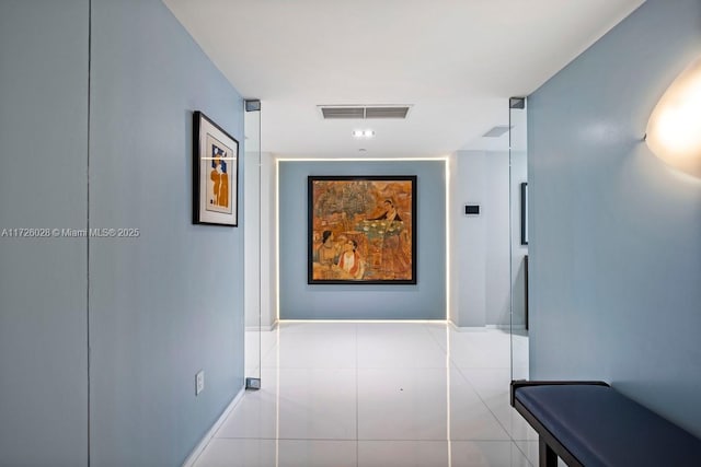 hall featuring light tile patterned floors, visible vents, and baseboards