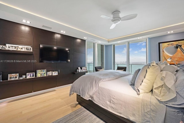 bedroom with ceiling fan, recessed lighting, visible vents, light wood-style floors, and a raised ceiling