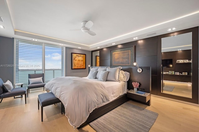 bedroom featuring a ceiling fan, recessed lighting, a raised ceiling, and light wood-style flooring