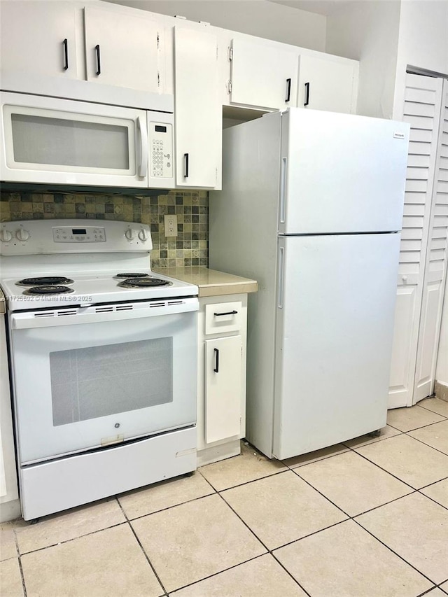 kitchen featuring white appliances, light tile patterned floors, tasteful backsplash, and white cabinetry