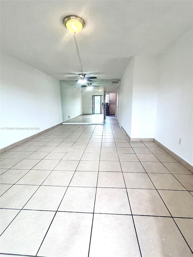 unfurnished room featuring a textured ceiling, ceiling fan, and light tile patterned floors