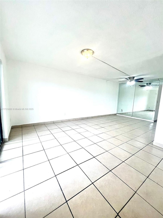 spare room featuring ceiling fan, light tile patterned flooring, and a textured ceiling