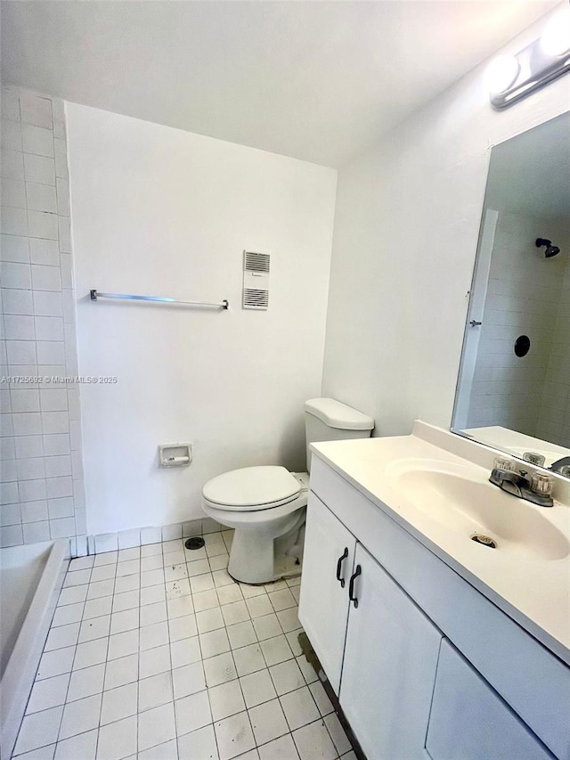 bathroom with toilet, vanity, tile patterned floors, and tiled shower