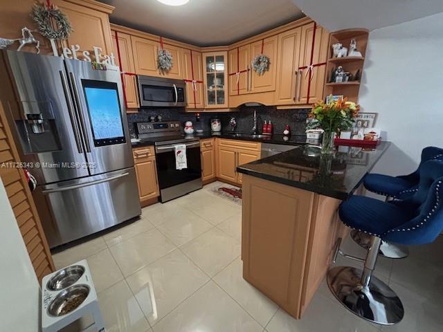 kitchen featuring backsplash, kitchen peninsula, sink, light tile patterned flooring, and appliances with stainless steel finishes