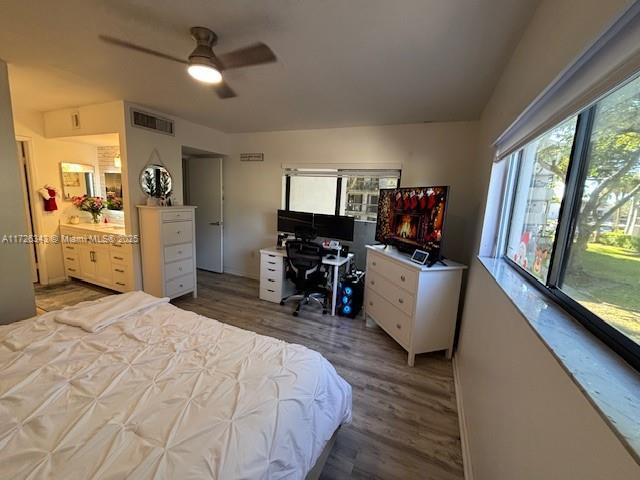 bedroom featuring ceiling fan, multiple windows, and wood-type flooring