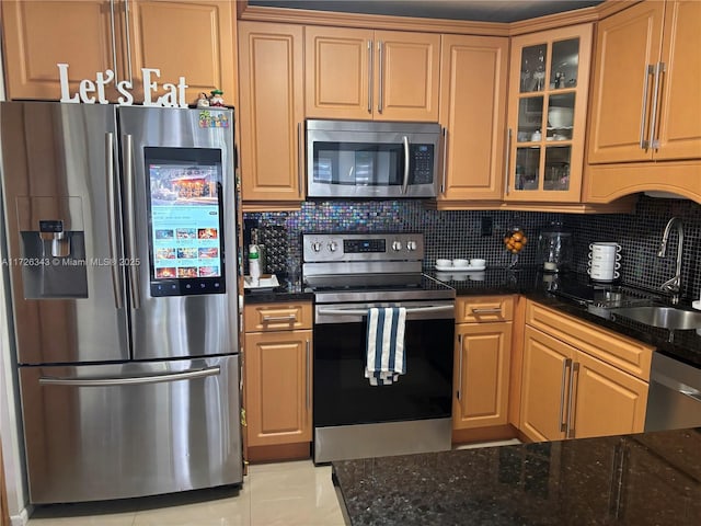 kitchen featuring dark stone counters, light tile patterned floors, appliances with stainless steel finishes, and tasteful backsplash