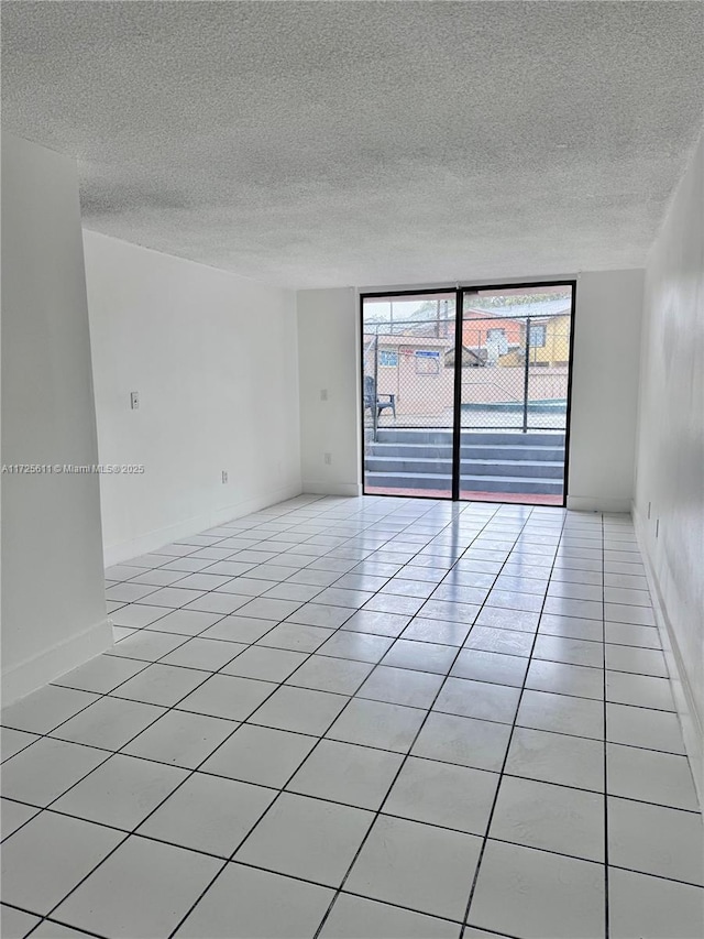 unfurnished room with expansive windows, light tile patterned floors, and a textured ceiling