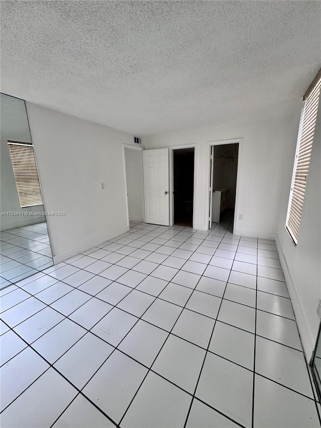 unfurnished room with light tile patterned floors, visible vents, and a textured ceiling