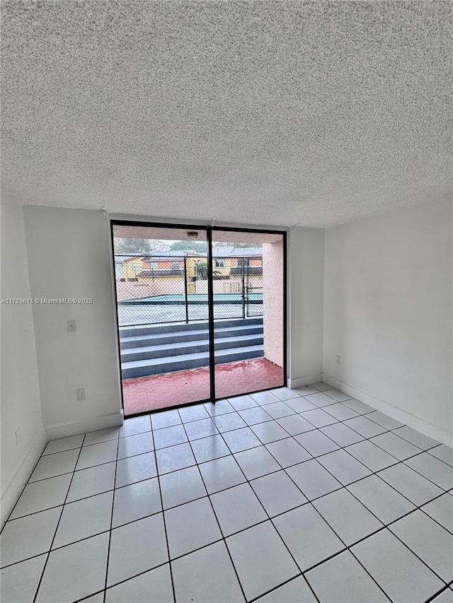 spare room featuring a textured ceiling, light tile patterned floors, and floor to ceiling windows
