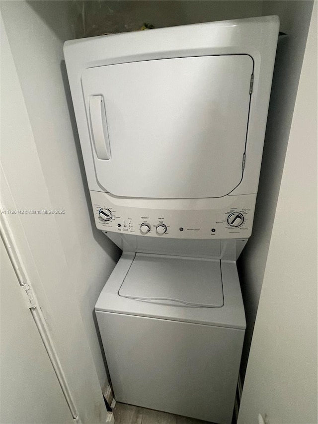 washroom featuring hardwood / wood-style flooring and stacked washer / drying machine