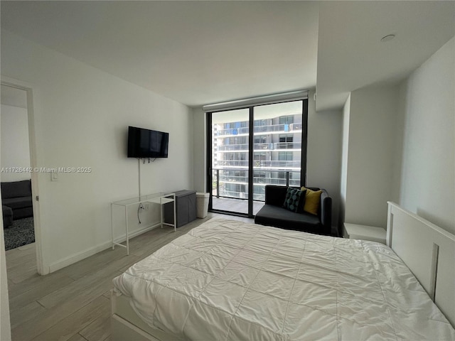 bedroom featuring a wall of windows, access to outside, and light hardwood / wood-style floors