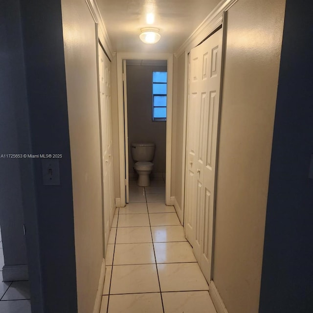 hallway featuring light tile patterned floors and crown molding