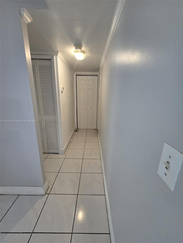 hall featuring light tile patterned flooring and crown molding